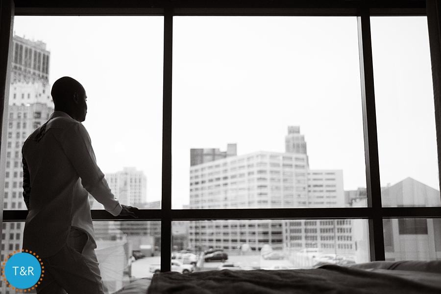 A groom looks out at the Detroit cityscape as he prepares for his wedding