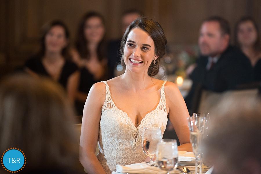 The bride, smiling wide, during the toasts