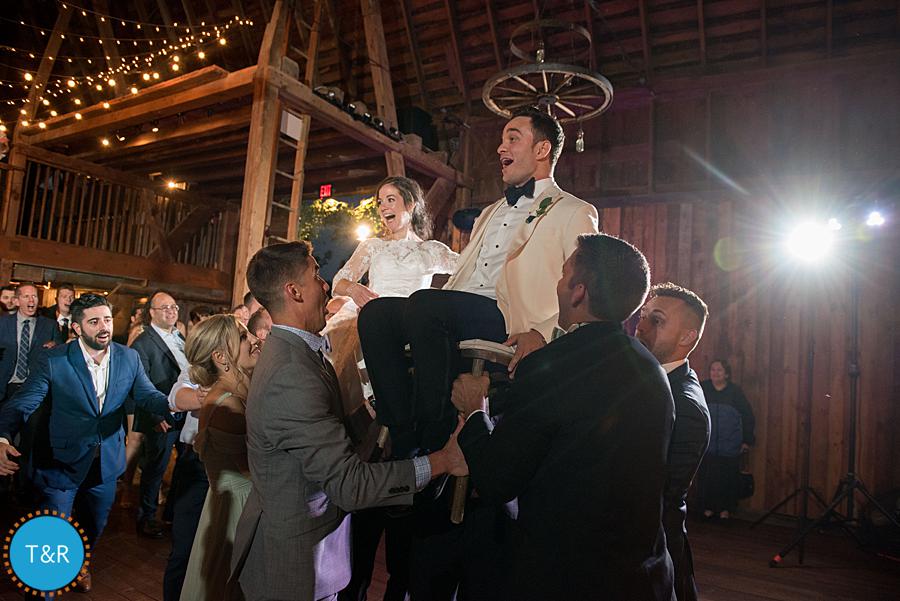 guests lift wedding couple up on chairs and dance