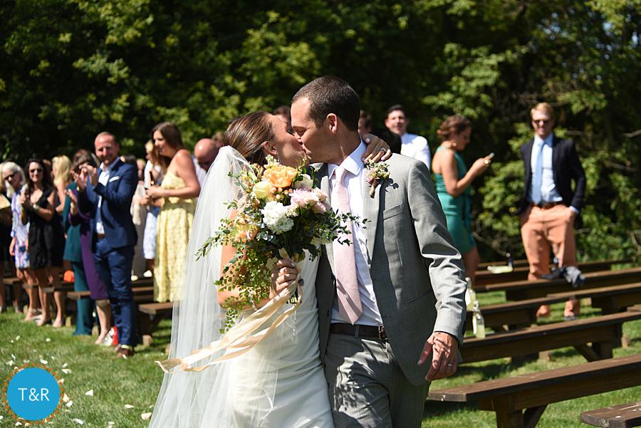 Bride and groom embrace and kiss after their wedding ceremony at Frutig Farms The Valley in Ann Arbor, MI