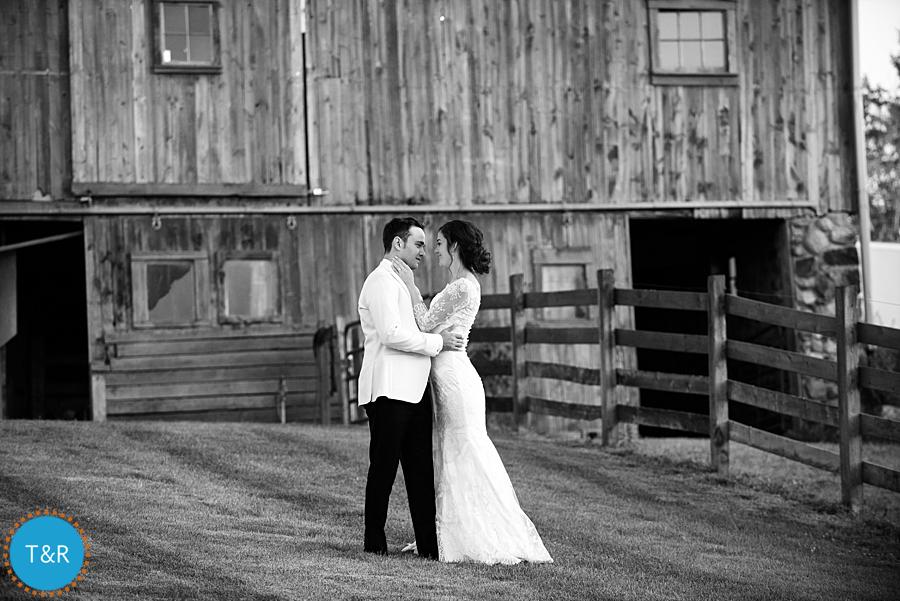 Bride and groom embrace in front of the barn at Frutig Farms Misty Farm during their Ann Arbor wedding reception