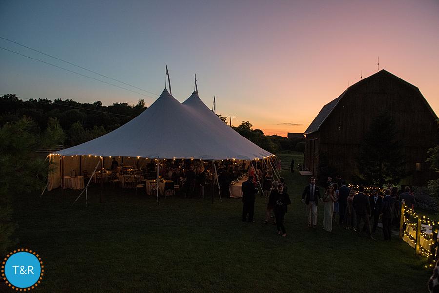 An exterior view of the tent and the barn in the evening at Frutig Farms Misty Farm during the Ann Arbor wedding reception