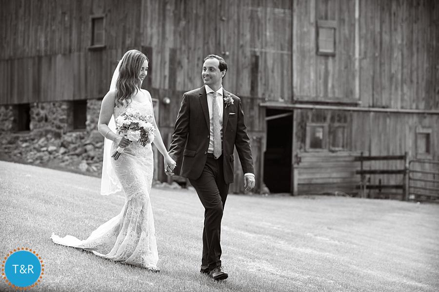 Black and white photo of bride and groom taking a walk at Frutig Farms Misty Farm during their wedding reception