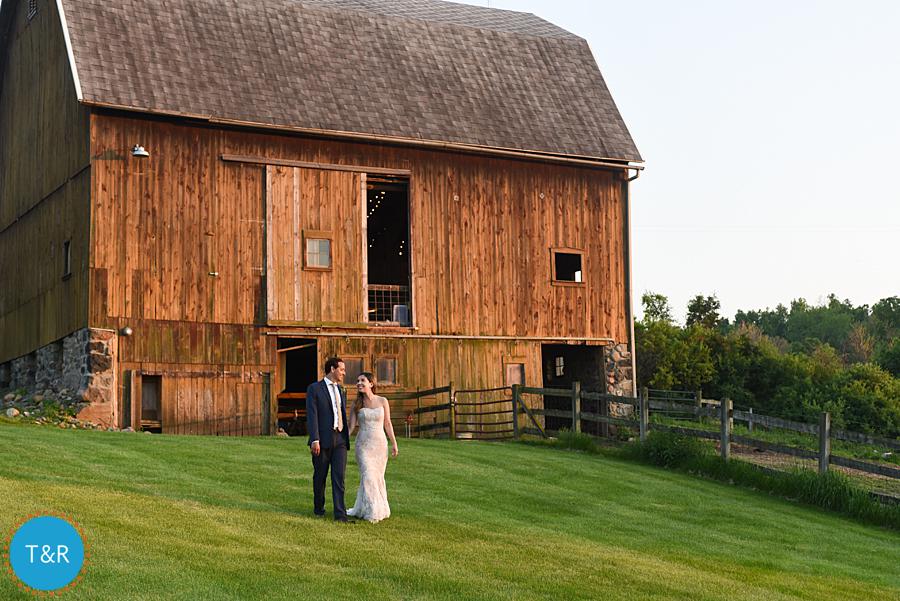Bride and groom take a walk outside the barn at their Frutig Farms Misty Farm wedding reception