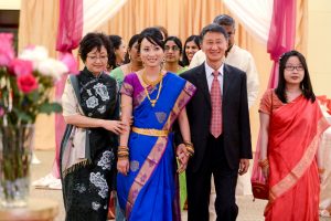 A bride wears a colorful hindu dress as she walks down the aisle